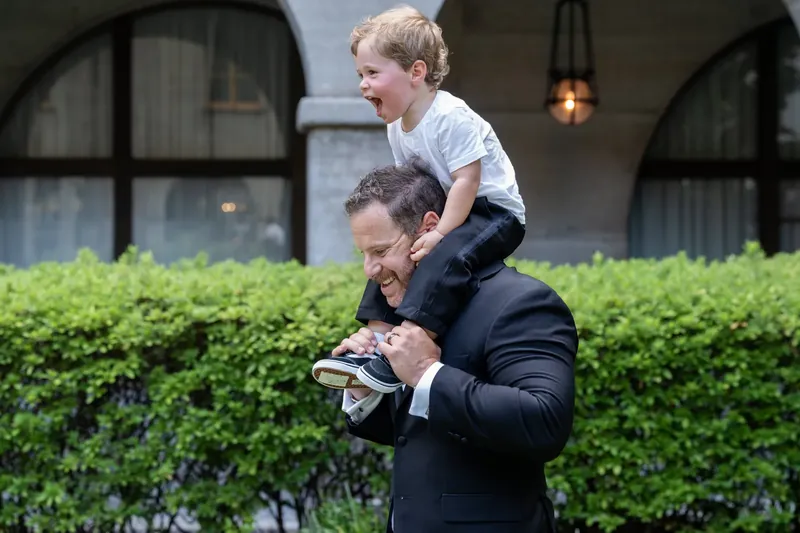 Russell holds their young child on his shoulders while walking through the museum's verdant grounds.