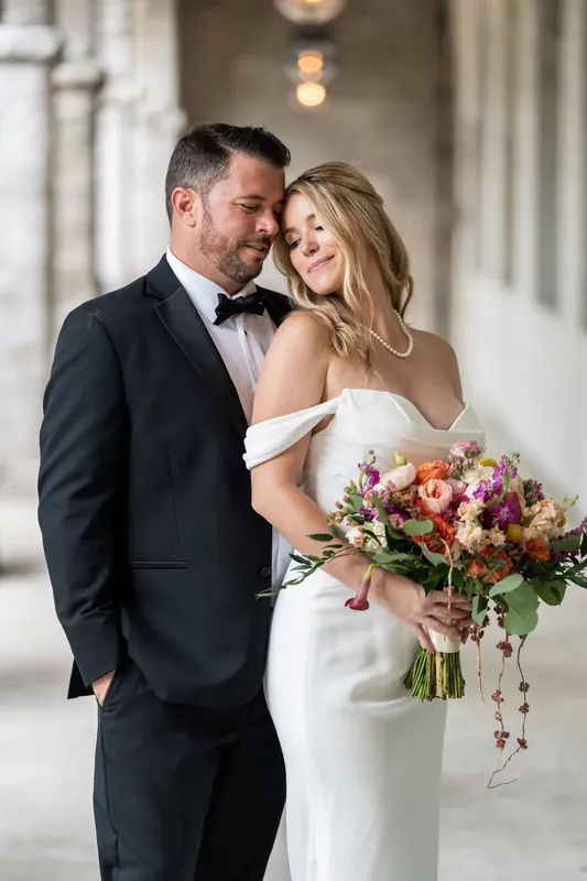 Russell gazes at Jenna as they pose in the colonnade, her cascading multicolored bouquet trailing with greenery.
