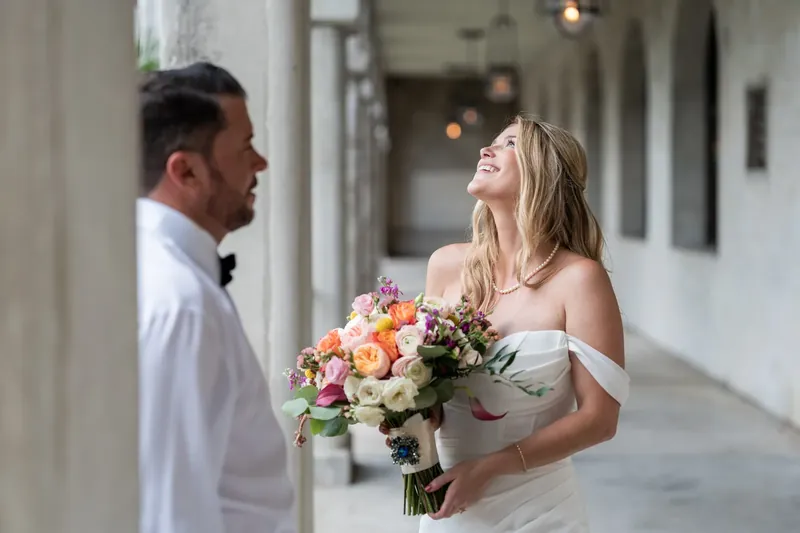 Russell and Jenna face each other smiling beneath the courtyard's arched loggia.
