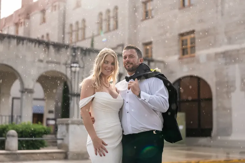 Jenna and Russell walk through the Lightner Museum Courtyard's stone arcade in their wedding attire.