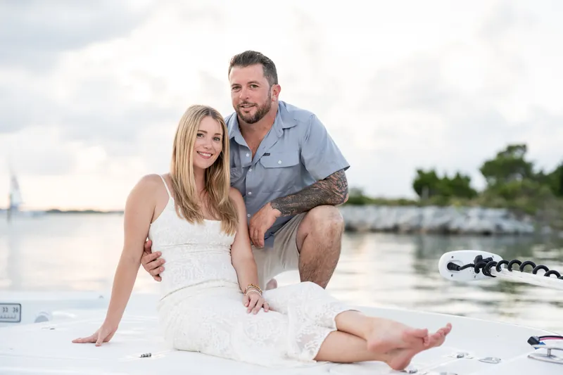 Jenna and Russell sit together on the boat at Matanzas Inlet, his arm around her as they look toward the waterway lined