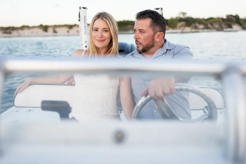 Jenna and Russell sit at the helm of their boat at Matanzas Inlet, smiling together as they look out across the water.