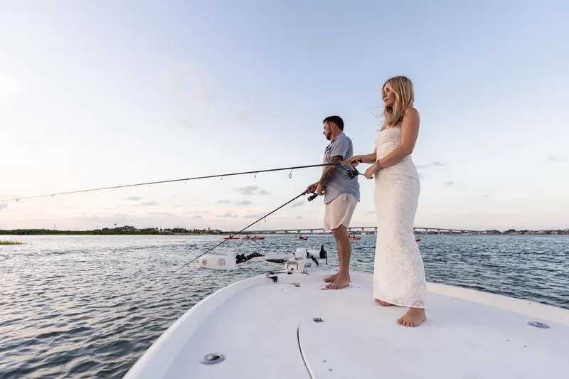 Russell and Jenna fish side by side on the boat's deck, both holding their rods as the inlet's waters sparkle around them.