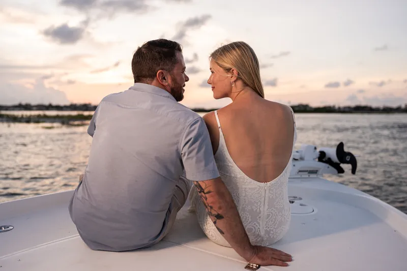 Russell and Jenna sit close together on the boat deck, foreheads nearly touching as they gaze at each other with the water