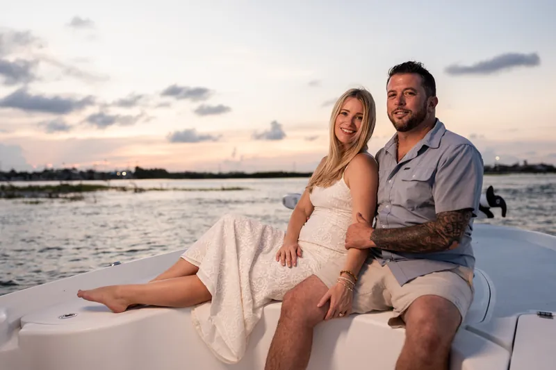 Reclining together on the boat's white seating, Russell and Jenna lean into each other against the dusky sky and calm water