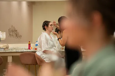 Bride in white robe getting makeup applied in luxury bridal suite