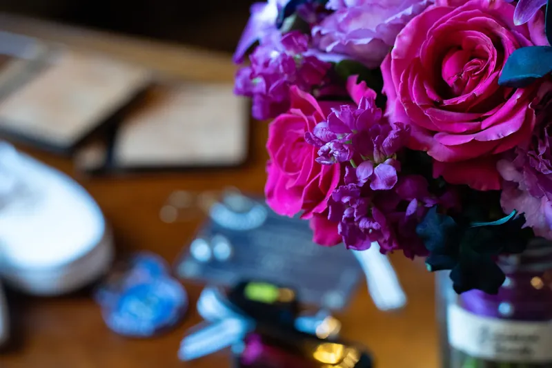 Close-up of vibrant magenta and purple roses in a bouquet with blurred details in the background.