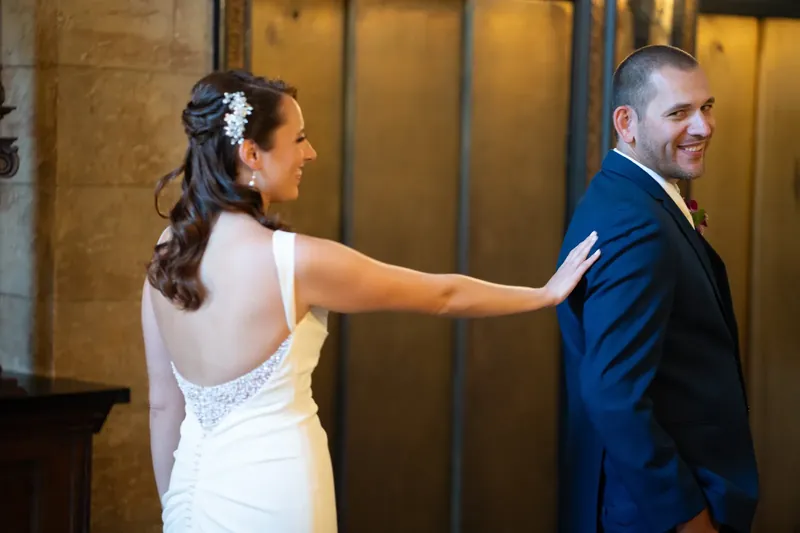 Jessica reaches toward John's back as they stand near gold-framed doors at The Treasury on the Plaza.