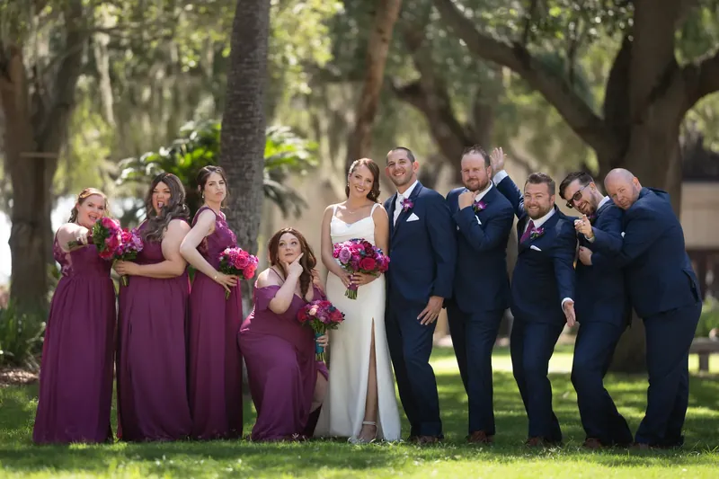 Wedding party lined up under live oaks at Plaza de la Constitución: Jessica and John in center, bridesmaids in burgundy, groomsmen in navy.