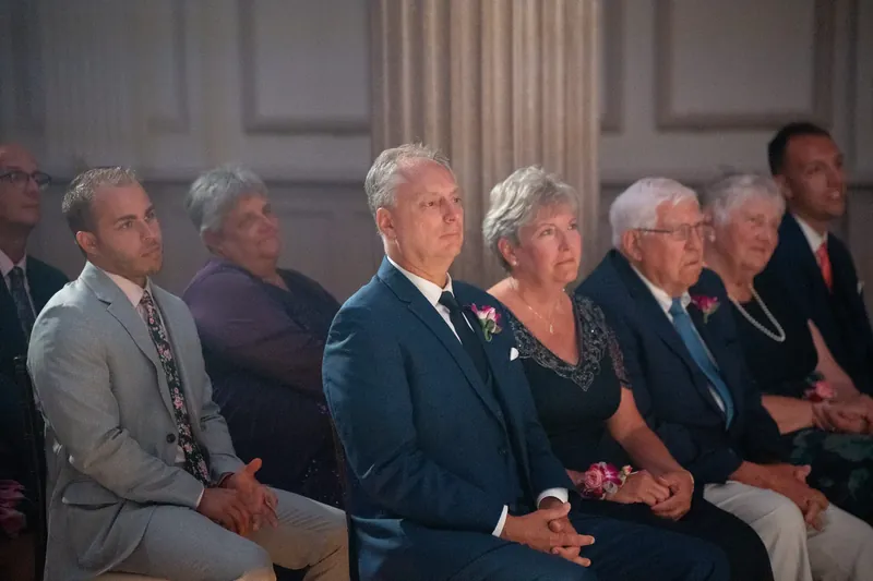 Family members sit in the front row, watching intently during the ceremony at The Treasury on the Plaza.