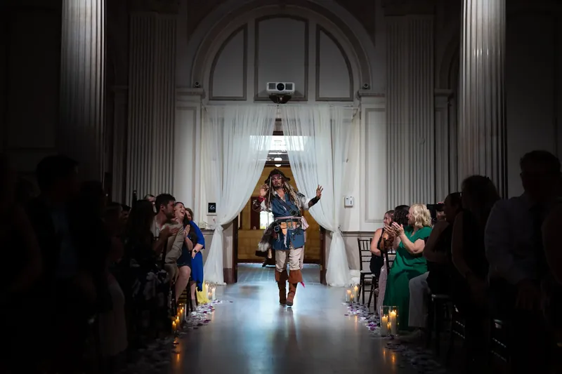 Jessica walks down a columned aisle at The Treasury toward waiting guests holding sparklers on both sides.