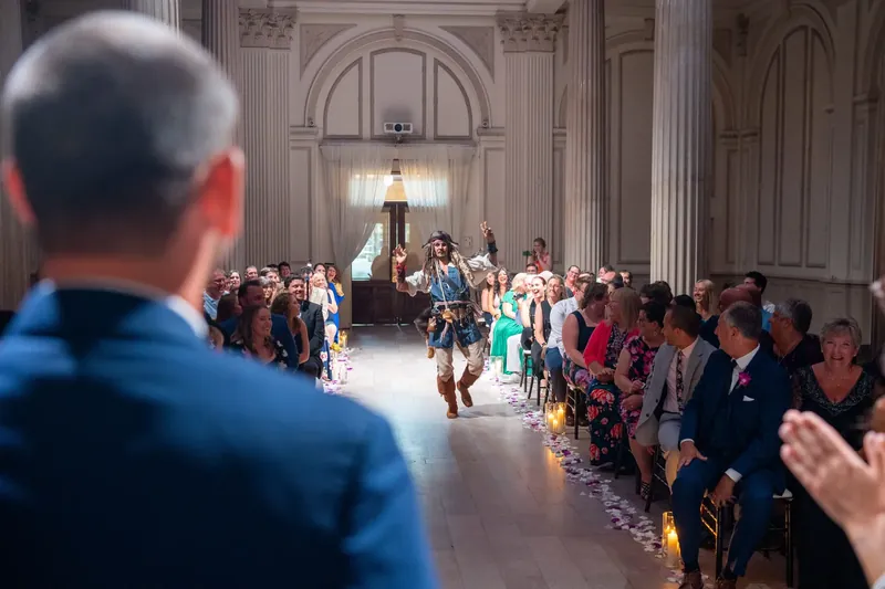 The pirate performer strides down the aisle at The Treasury while guests seated on both sides watch and applaud.