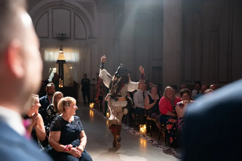 A pirate performer dances energetically before seated guests in the grand hall at The Treasury on the Plaza, St. Augustine.