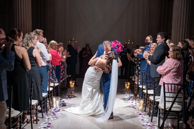 John dips Jessica in a kiss as guests cheer along the aisle lined with candlelight at The Treasury on the Plaza.