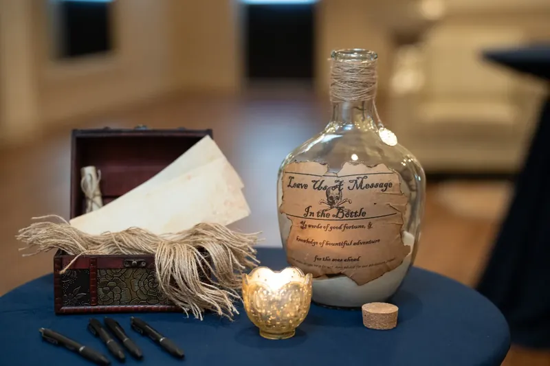 A glass bottle labeled "Love Potion" sits on a navy table with feathered props and a gold ornament.