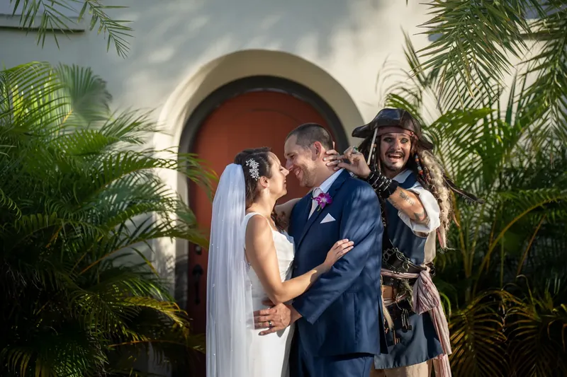 Jessica and John kiss beneath a terracotta arch surrounded by tropical greenery in downtown St. Augustine.