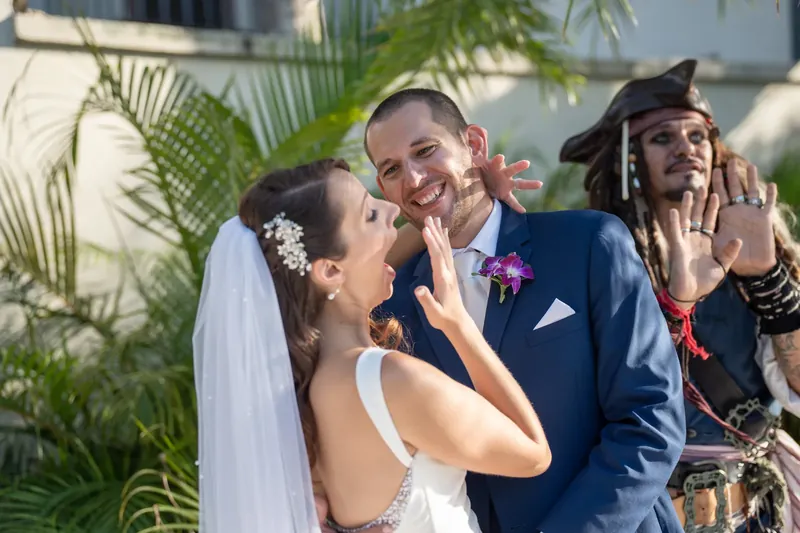 Jessica and John laugh together while a costumed pirate performer gestures beside them.