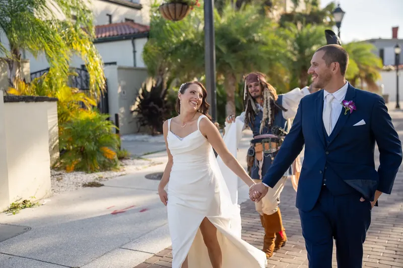 Jessica and John stroll down a tree-lined pedestrian path in downtown St. Augustine, hand in hand and smiling.