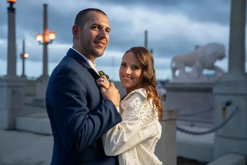 John and Jessica embrace and smile at the St. Augustine Bayfront, lit structures glowing softly behind them.