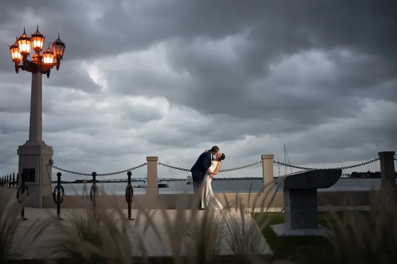 John dips Jessica under a street lamp on the bayfront while dramatic clouds gather overhead.