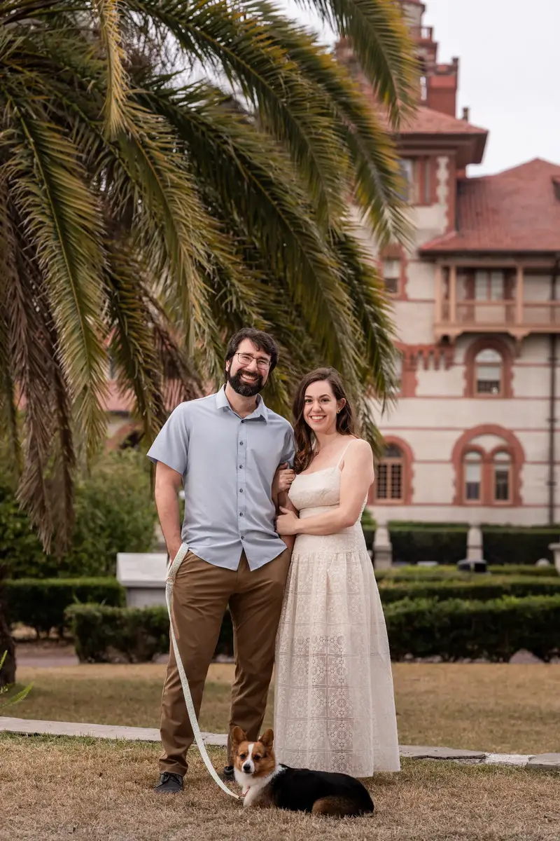 Jillian and Jason standing together with Bonnald in front of Flagler College palm trees