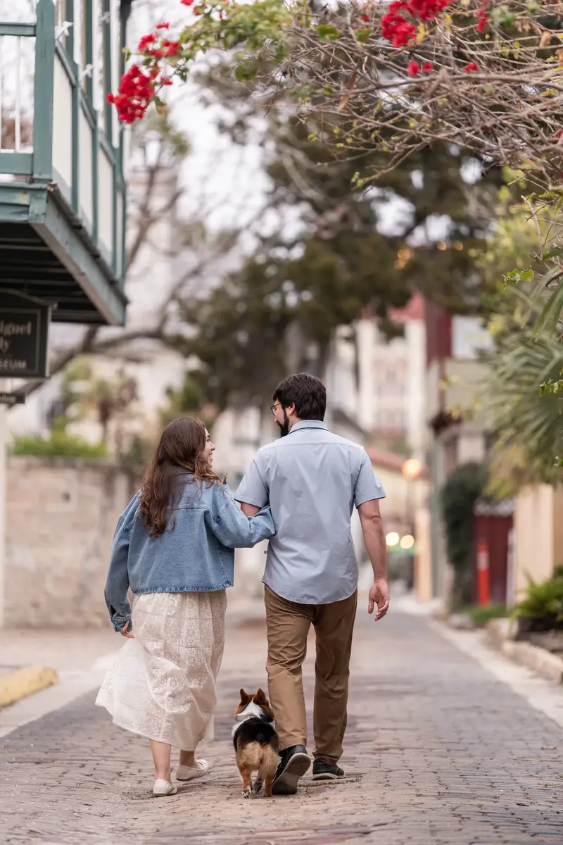Jillian and Jason walking away with Bonnald on Aviles Street with bougainvillea overhead