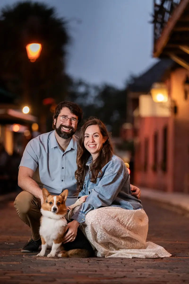 Jillian, Jason, and Bonnald sitting together at dusk with warm street lights in downtown St. Augustine