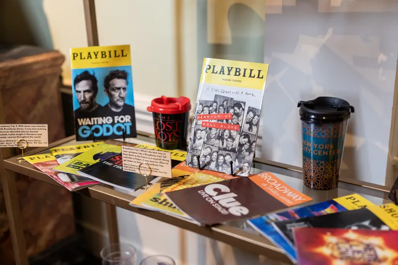 Playbills and theater programs, including "Waiting for Godot," are displayed as part of the wedding's décor alongside candles and colored glassware.