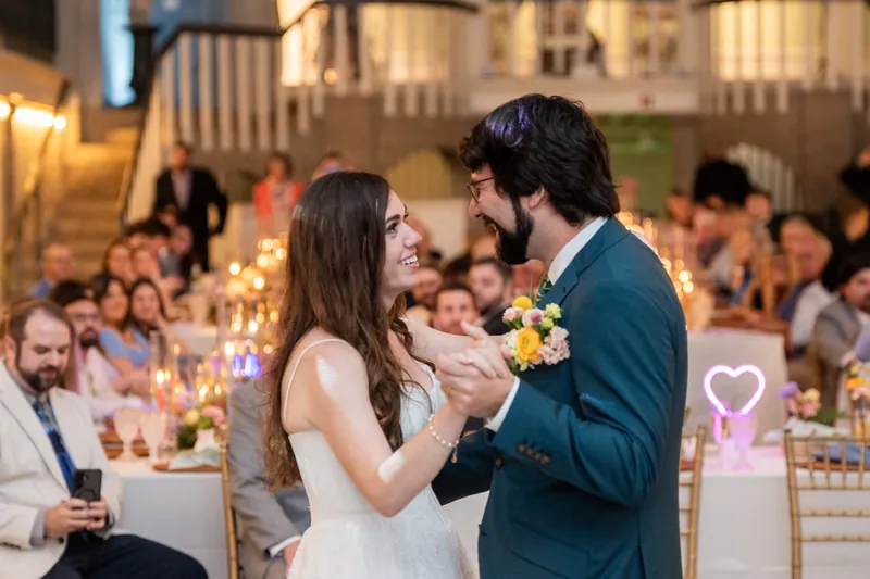 Jillian and Jason share their first dance surrounded by seated guests in the Lightner Museum's grand hall.