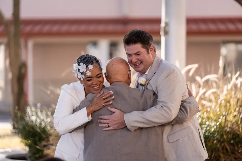 Newlyweds embrace a family member after the ceremony
