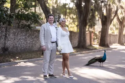 Newlyweds pose on Magnolia Street with a peacock walking by in the background