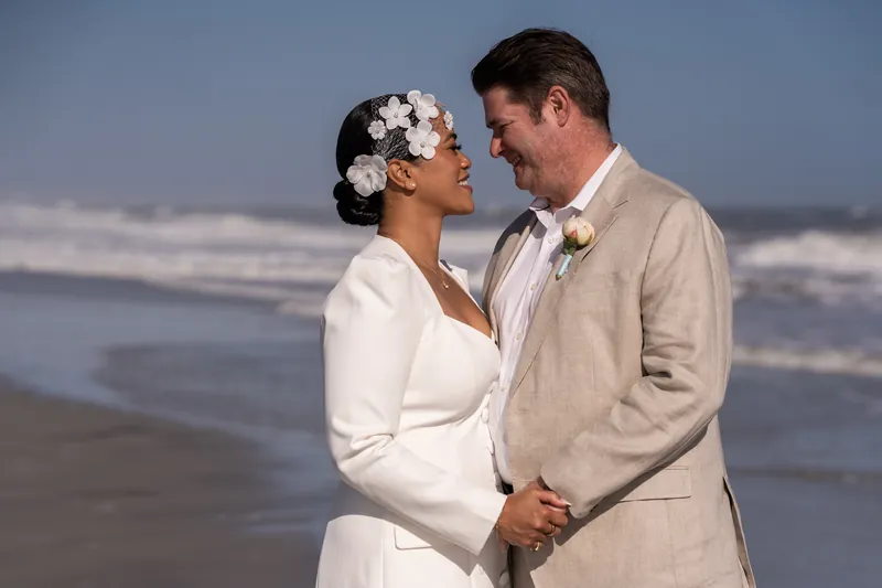 Josh and Diane smile at each other with ocean waves behind them at Vilano Beach
