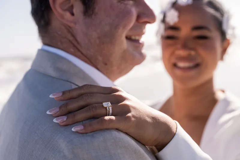 Ring detail shot showing bride's hand on groom's shoulder at Vilano Beach