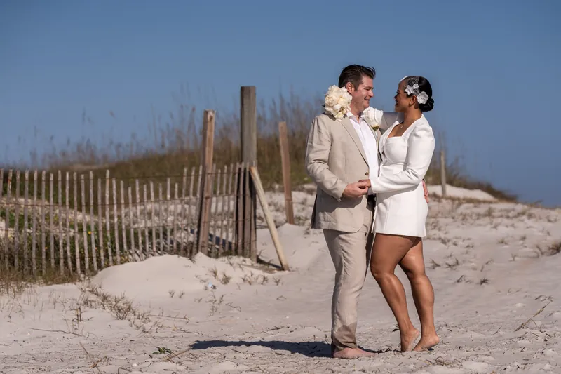 Couple portrait in front of sand dunes and beach fence at Vilano Beach