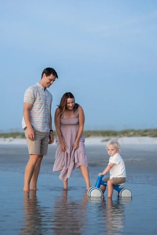 Jourdan and partner wade through shallow water with their toddler at St. Augustine Beach.