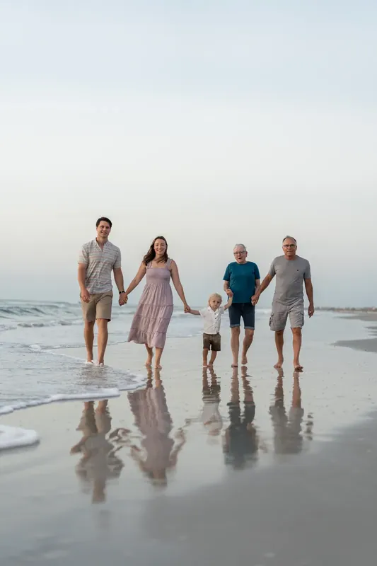 Jourdan's family wades in the wet sand at the shore, with the smallest child positioned in the middle of the group.