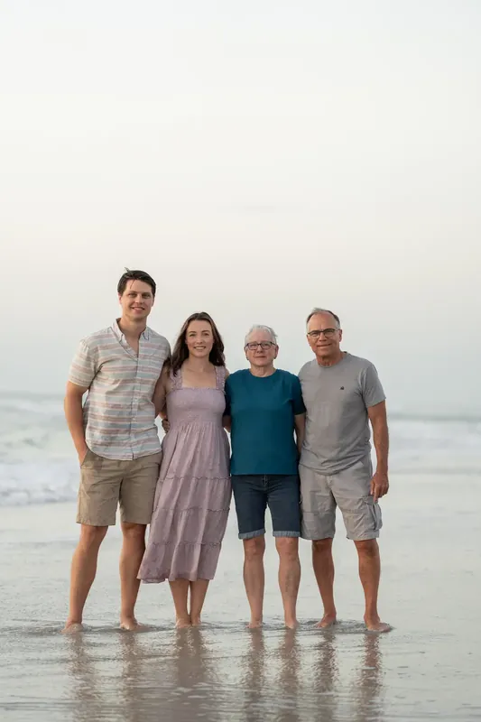 Four adults stand knee-deep in the ocean at St. Augustine Beach, the child between them looking directly ahead.