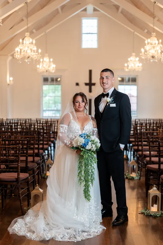 Julia and William stand together at the altar holding a cascading greenery bouquet in The White Room's chapel.