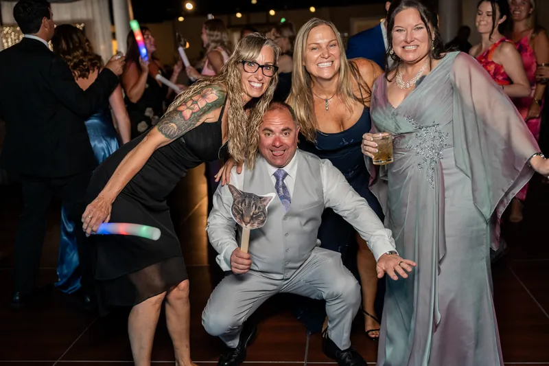 A man crouches playfully while surrounded by guests dancing and celebrating at The White Room, St. Augustine.