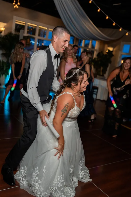 Two people dance at The White Room, one in a suit dipping their partner in a lace gown as guests watch.