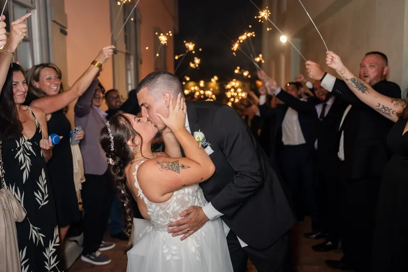 Guests holding sparklers frame two people embracing on the dance floor during their sparkler exit.
