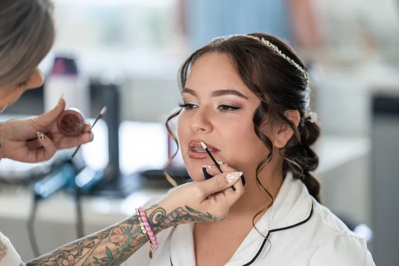 A person in a white shirt gets lipstick applied during morning preparations at the Airbnb in St. Augustine.