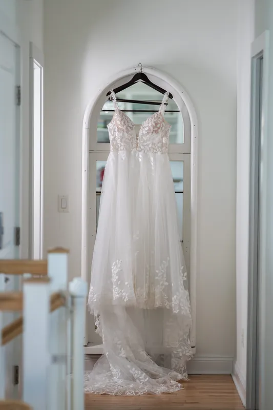 A white lace wedding gown with a long train hangs in an arched doorway of the St. Augustine Airbnb.