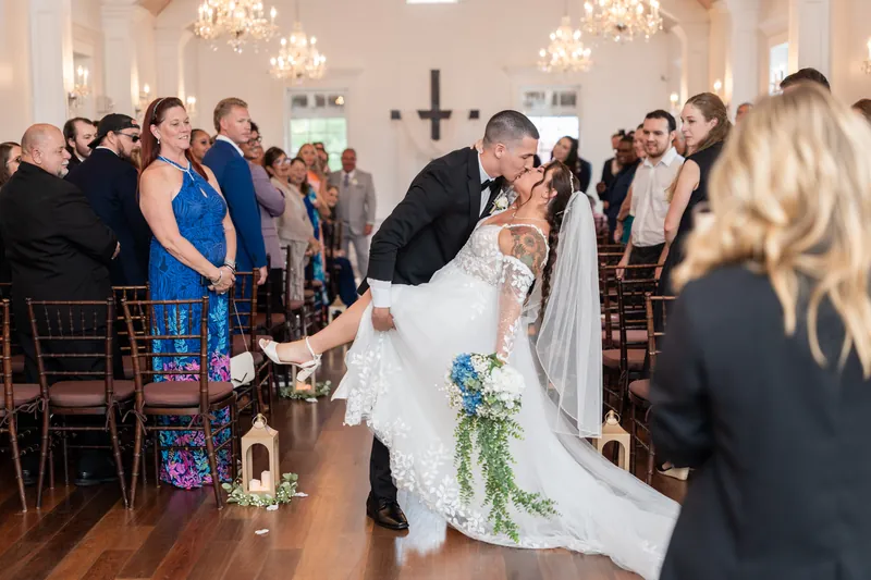 The newlyweds kiss as guests rise and applaud in the aisle at The White Room's chapel.