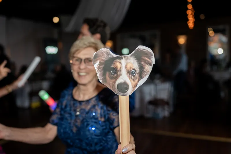 A guest in glasses holds up a dog-shaped fan during the reception at The White Room, St. Augustine.