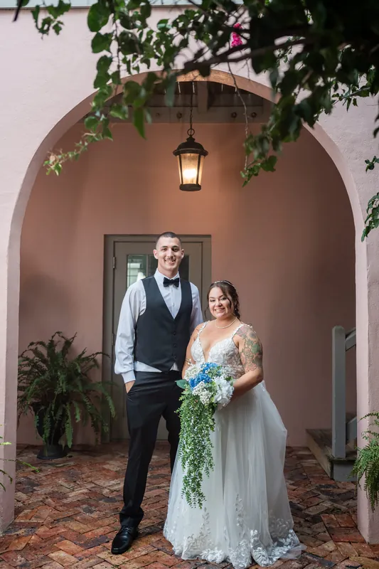 Two people stand beneath a pale archway framed by hanging greenery at The White Room, St. Augustine.