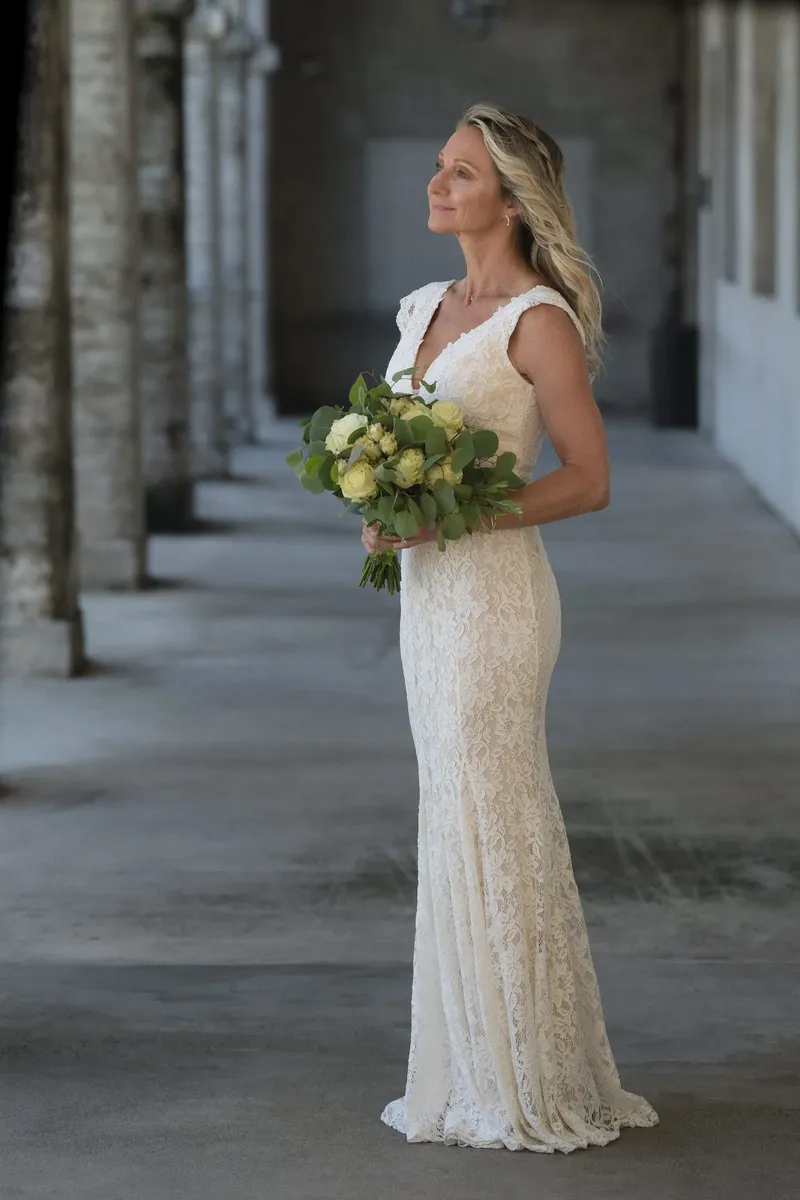 Full-length bridal portrait with lace dress and eucalyptus bouquet