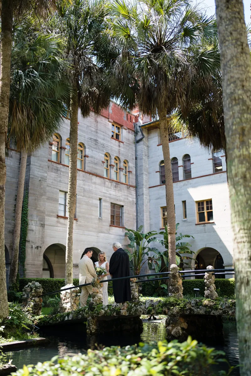 Wide ceremony shot on the bridge with palm trees and Spanish architecture