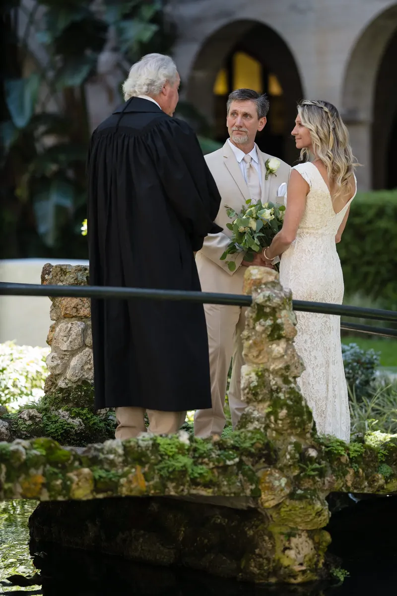 Ceremony on the coquina stone bridge over the reflecting pond with officiant
