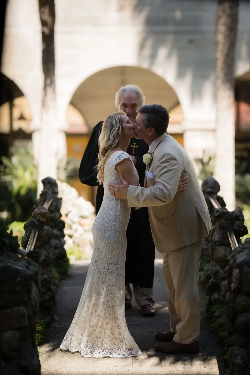 First kiss on the bridge with officiant and Spanish arches behind